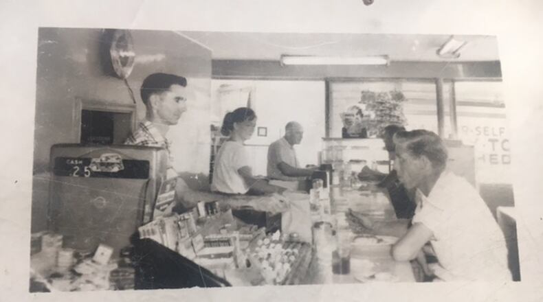 Annette Johnson is in the middle in this photo taken in Roy’s Drive-In, and her husband Roy is the dark-haired man behind the counter in the foreground.