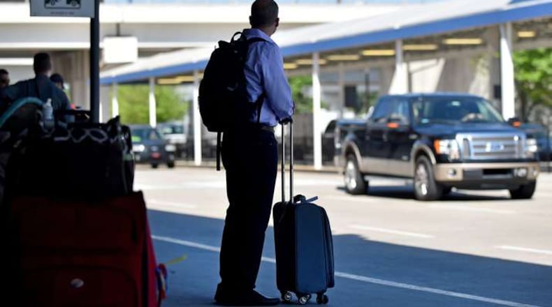 An arriving passenger waits for a ride at Hartsfield Jackson International Airport. BRANT SANDERLIN/BSANDERLIN@AJC.COM