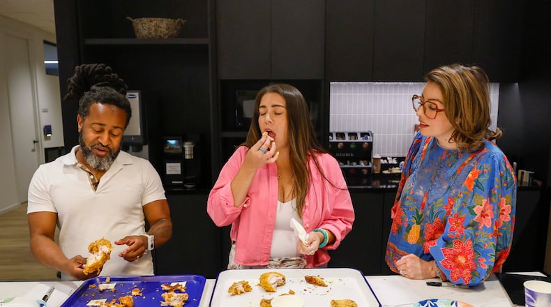 Daniela Cintron, editor at Discover Atlanta, center, reacts as she tastes a piece of fried chicken alongside Justin Brown, ATL50 expert panelist, during a contest to find Atlanta’s best fried chicken, held on Tuesday, Aug. 25, 2026, at the AJC office in Midtown. (Miguel Martinez/AJC)