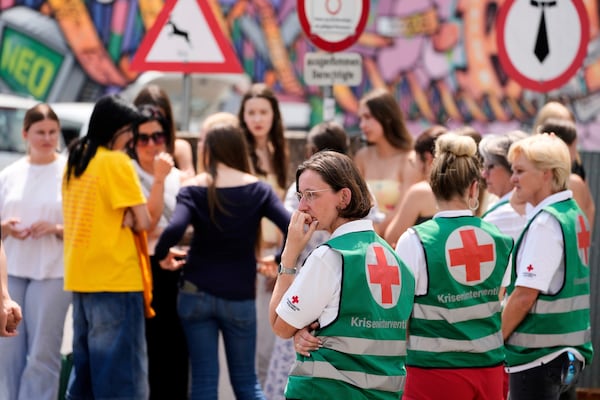 Medical helpers stand outside a school where a former student opened fire the day before fatally wounding several people and injuring many others before taking his own life, Graz, Austria, Wednesday, June 11, 2025. (AP Photo/Darko Bandic)