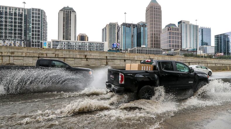 Motorists contend with pooling water along Techwood Drive at 16th Street in downtown Atlanta on Monday, July 10, 2023. As the risk of climate-fueled disasters grows, Georgia and the Metro Atlanta region are developing their first-ever climate plans. (John Spink / John.Spink@ajc.com)
