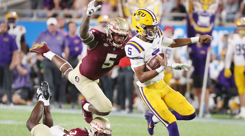 LSU quarterback Jayden Daniels (5) outruns leaping FSU defensive lineman Jared Verse (5) during the 2023 Camping World Kickoff college football game at Camping World Stadium in Orlando, Florida on Sunday, Sept. 3, 2023. (Stephen M. Dowell/Orlando Sentinel/TNS)