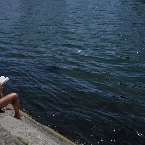 A man reads a book while sitting in the sun along the Seine River in Paris, Monday, May 25, 2026. (AP Photo/Michel Euler)