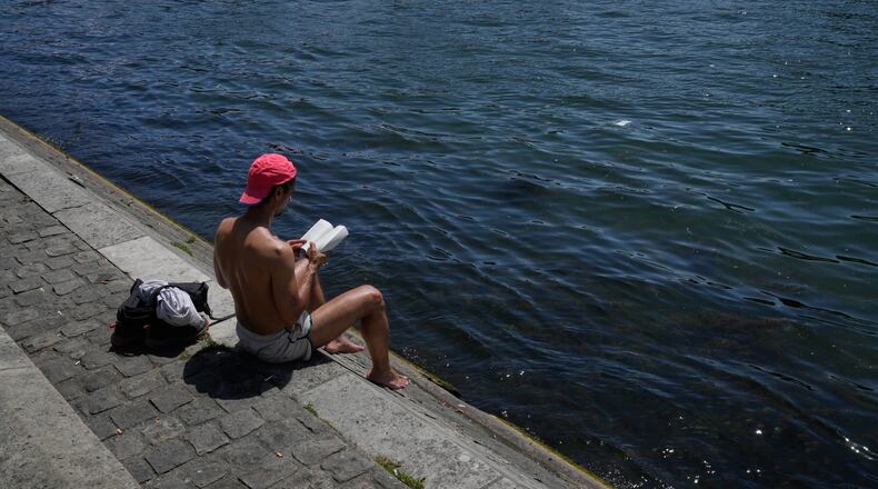 A man reads a book while sitting in the sun along the Seine River in Paris, Monday, May 25, 2026. (AP Photo/Michel Euler)