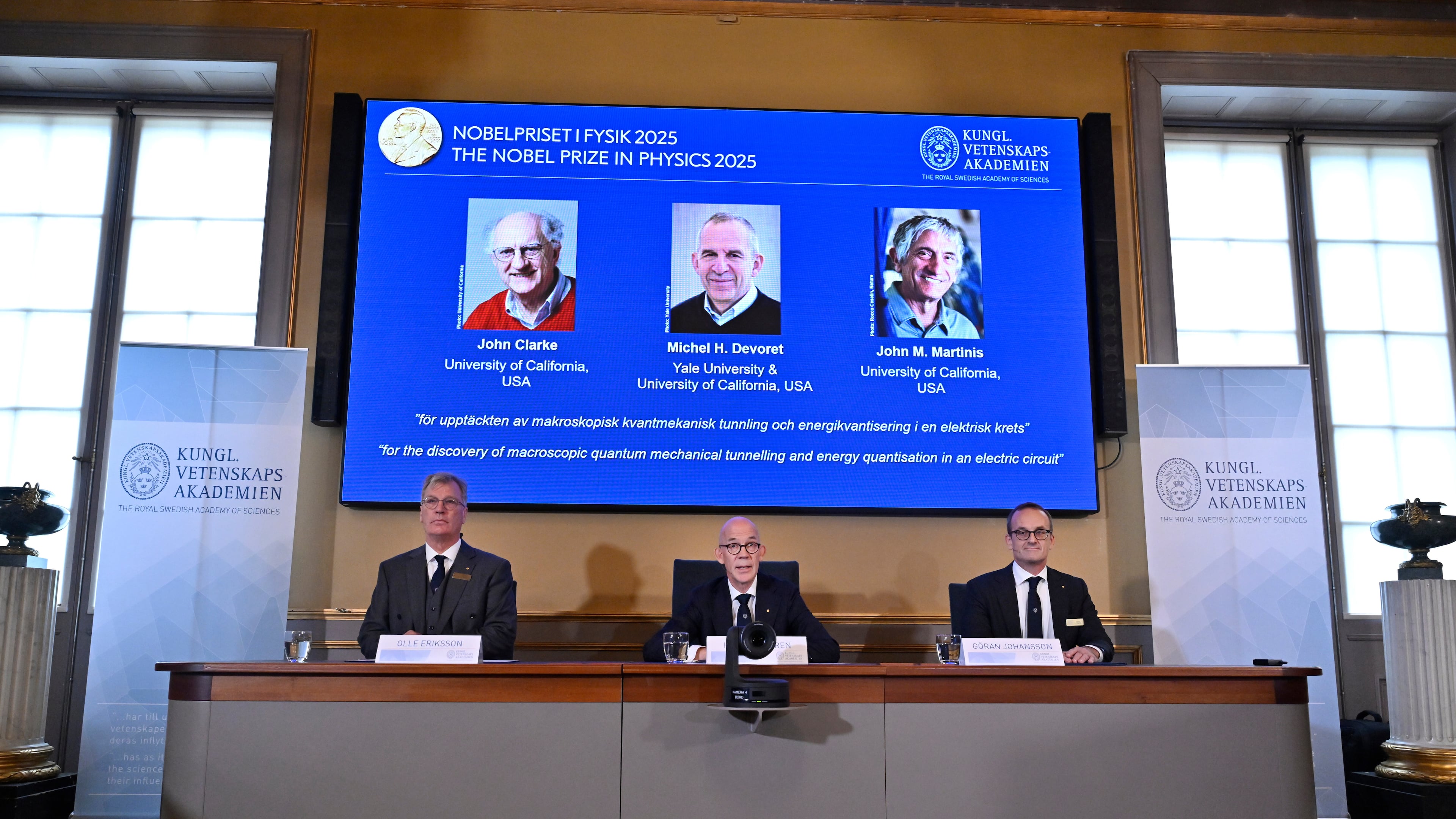 From left, Chair of the Nobel Committee for Physics Chair Olle Eriksson, Secretary General of the Swedish Academy of Sciences Hans Ellegren and Member of the Nobel Committee for Physics Goran Johansson announce John Clarke, Michel H Devoret and John M. Martinis, on screen behind, as the recipients the Nobel Prize in Physics, at the Nobel Assembly of the Karolinska Institutet, in Stockholm, Sweden, Tuesday, Oct. 7, 2025. (Christine Olsson/TT News Agency via AP)