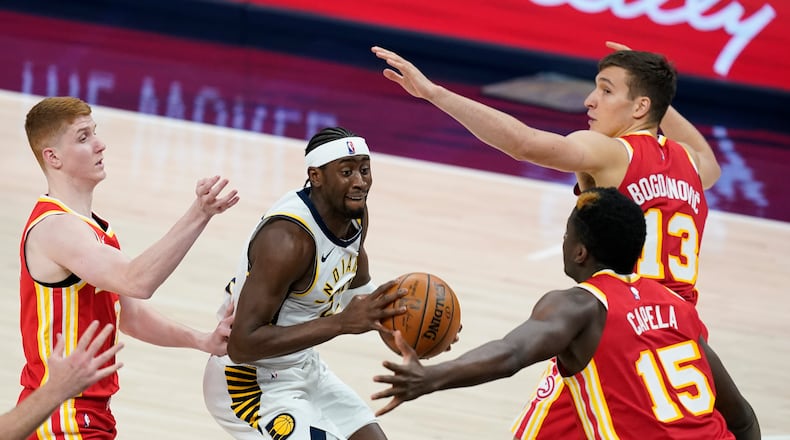 Indiana Pacers' Caris LeVert (22) looks for a shot between Atlanta Hawks' Bogdan Bogdanovic (13), Clint Capela (15) and Kevin Huerter during the second half of an NBA basketball game Thursday, May 6, 2021, in Indianapolis. (AP Photo/Darron Cummings)