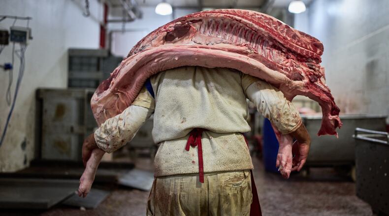 A worker carries pork inside a butcher shop at the Mataderos meat market in Buenos Aires, Argentina, Thursday, May 14, 2026. (AP Photo/Rodrigo Abd)