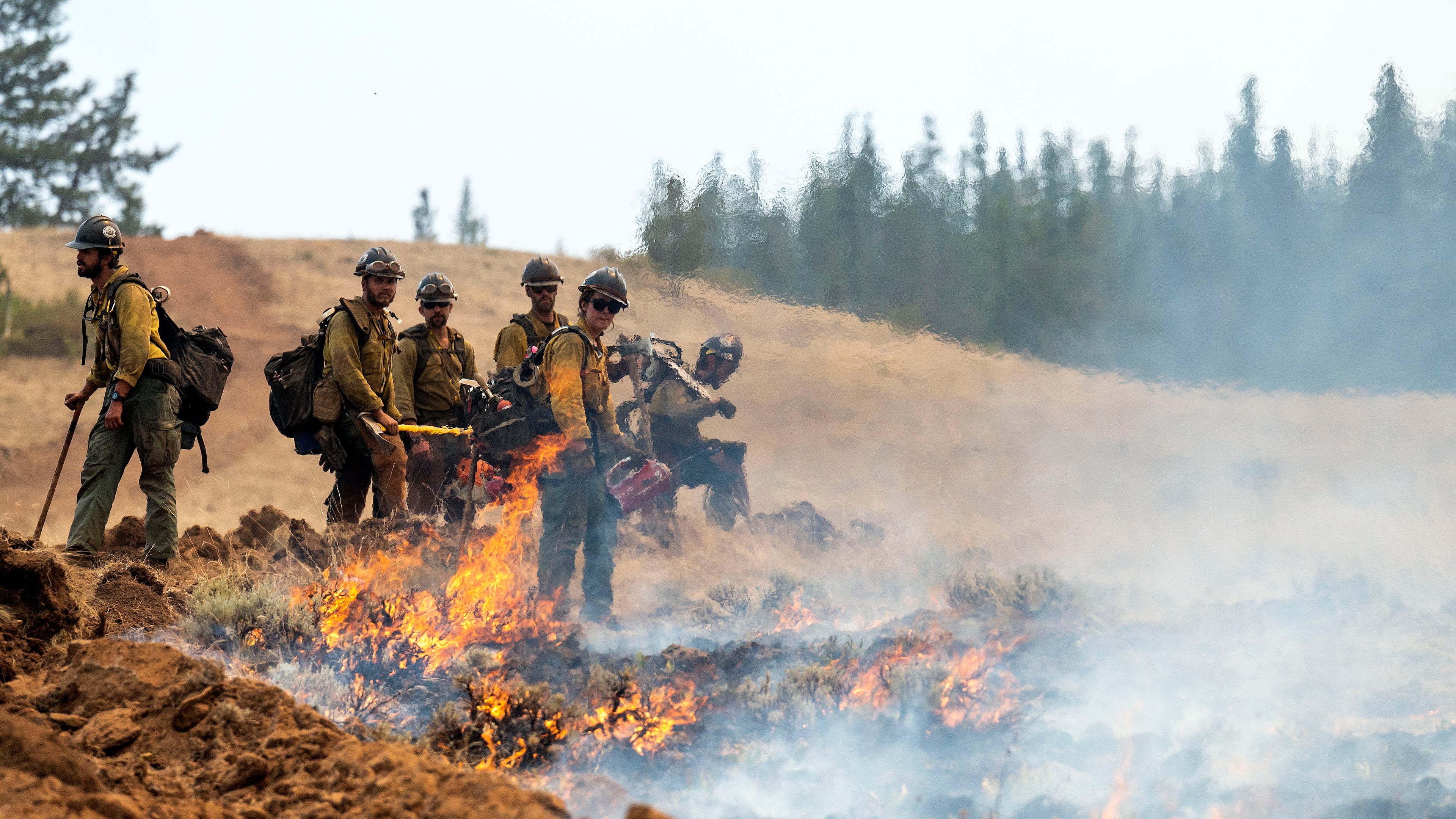 FILE - A wildland fire crew looks on after setting a fire line on Harlow Ridge above the Lick Creek Fire, July 12, 2021, south of Asotin, Wash. (Pete Caster/Lewiston Tribune via AP, File)
