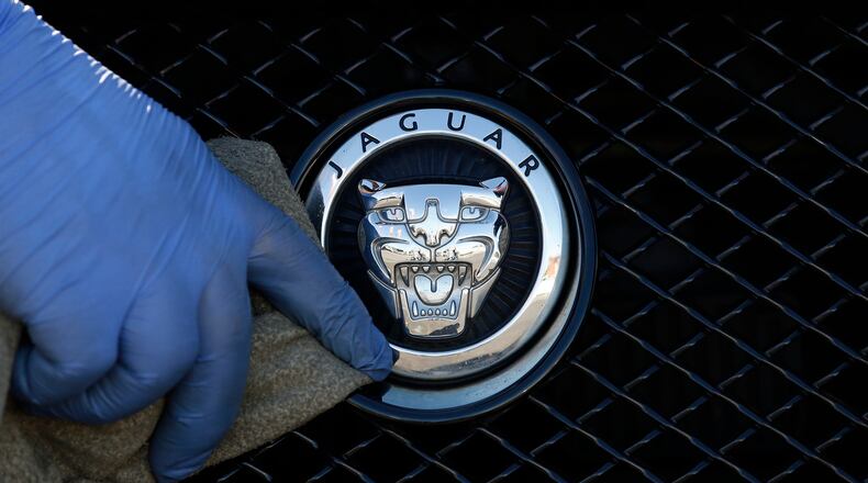 FILE - A worker polishes a Jaguar logo on a car at a Jaguar dealer in London, Wednesday Sept. 28, 2016. (AP Photo/Frank Austin, File)