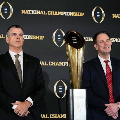 Miami head coach Mario Cristobal and Indiana head coach Curt Cignetti pose with the trophy after a news conference ahead of the College Football Playoff national championship game between Miami and Indiana, Sunday, Jan. 18, 2026, in Miami. The game will be played on Monday. (AP Photo/Chris Carlson)
