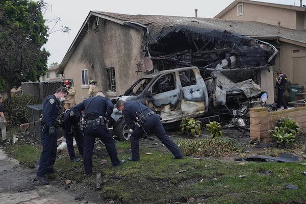 Authorities work the scene where a small plane crashed into a San Diego neighborhood, setting several homes on fire and forcing evacuations along several blocks early Thursday, May 22, 2025. (AP Photo/Gregory Bull)