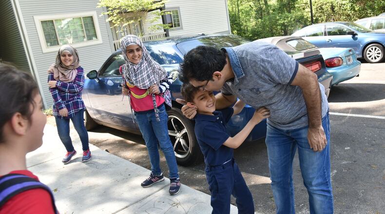 Yaser Musa kisses his son, Issa, 5, outside their Clarkston apartment as he waits for his other children (from left) Samar, 10, Nor Alhoda, 12, and Reem, 11, on April 13, 2017. HYOSUB SHIN / HSHIN@AJC.COM