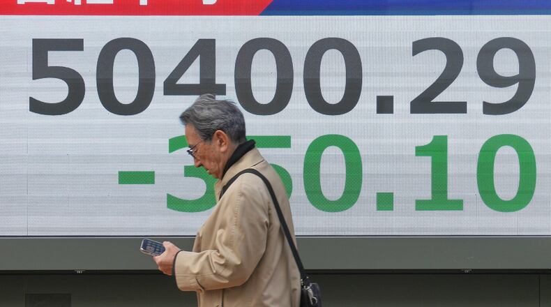 A person walks in front of an electronic stock board showing Japan's Nikkei index at a securities firm, Monday, Dec. 29, 2025, in Tokyo. (AP Photo/Eugene Hoshiko)