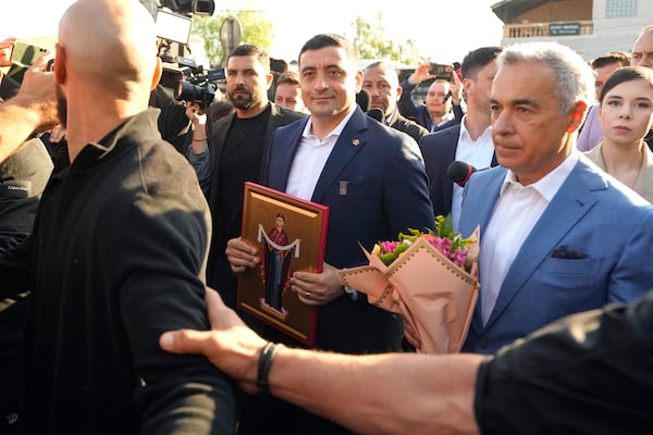 Presidential candidate George Simion, left, holds a religious icon as he walks with Calin Georgescu, winner of the first round of last year's annulled election, after casting his vote in the first round of the presidential election redo in Mogosoaia, Romania, Sunday, May 4, 2025. (AP Photo/Vadim Ghirda)