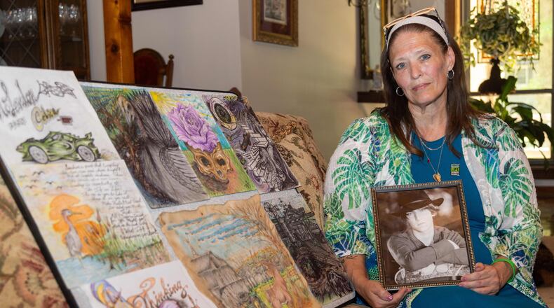 Dawn Mclendon sits beside some of her son Travis' artwork in her East Cobb home. She lost her son Travis, age 33, just before Mother's Day of 2023 to fentanyl poisoning. But before he left this world, he donated his liver to his mother and saved her life. PHIL SKINNER FOR THE ATLANTA JOURNAL-CONSTITUTION