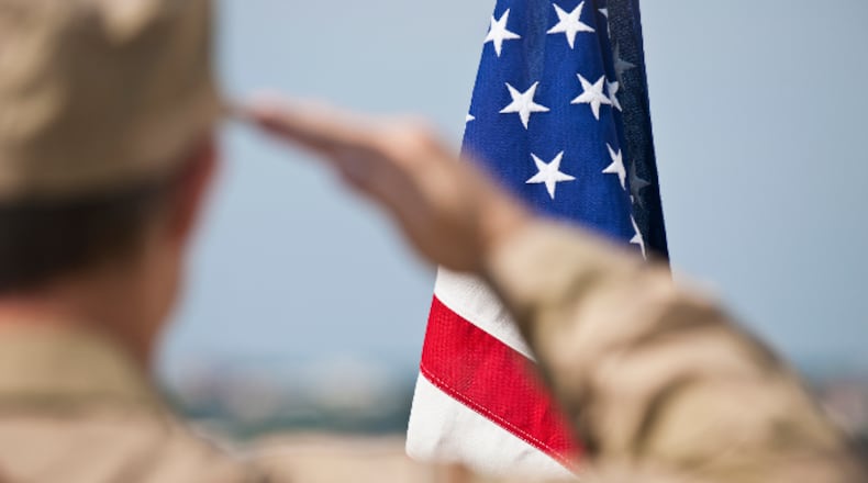 Soldier salutes flag (stock photo).