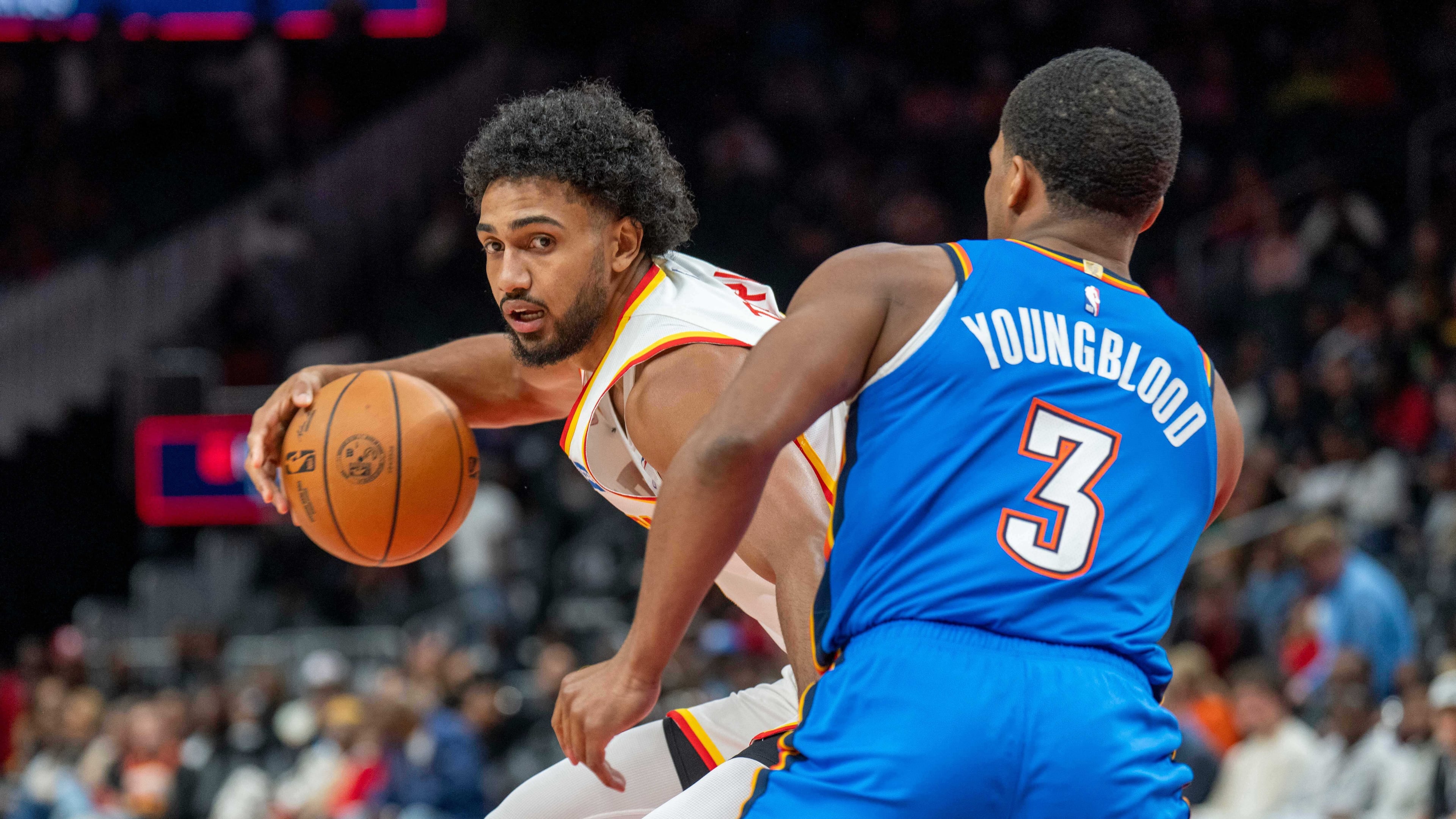 Atlanta Hawks forward Jacob Toppin, left, drives the ball against Oklahoma City Thunder guard Chris Youngblood (3) during the first half of an NBA basketball game, Saturday, Oct. 25, 2025, in Atlanta. (AP Photo/Erik Rank)