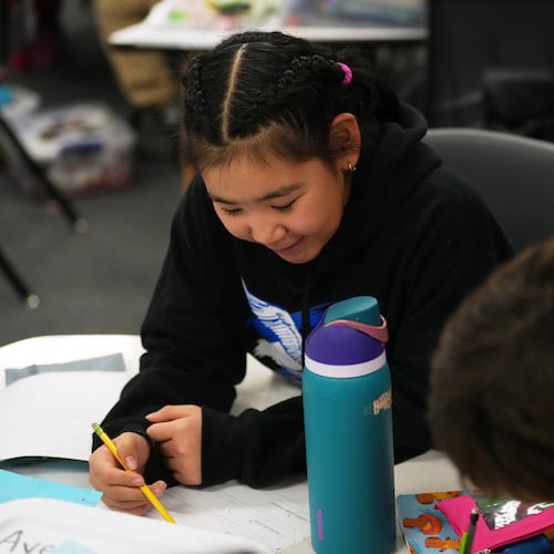 Rayann Martin, a 10-year-old displaced from the village of Kipnuk by ex-Typhoon Halong, left, talks with new classmate Lilly Loewen, 10, right, as they work in the Yup'ik language at College Gate Elementary, Thursday, Oct. 30, 2025, in Anchorage, Alaska. (AP Photo/Lindsey Wasson)