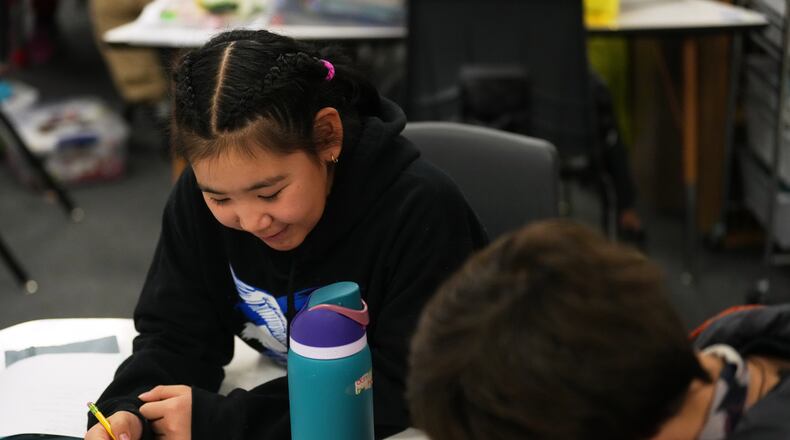 Rayann Martin, a 10-year-old displaced from the village of Kipnuk by ex-Typhoon Halong, left, talks with new classmate Lilly Loewen, 10, right, as they work in the Yup'ik language at College Gate Elementary, Thursday, Oct. 30, 2025, in Anchorage, Alaska. (AP Photo/Lindsey Wasson)