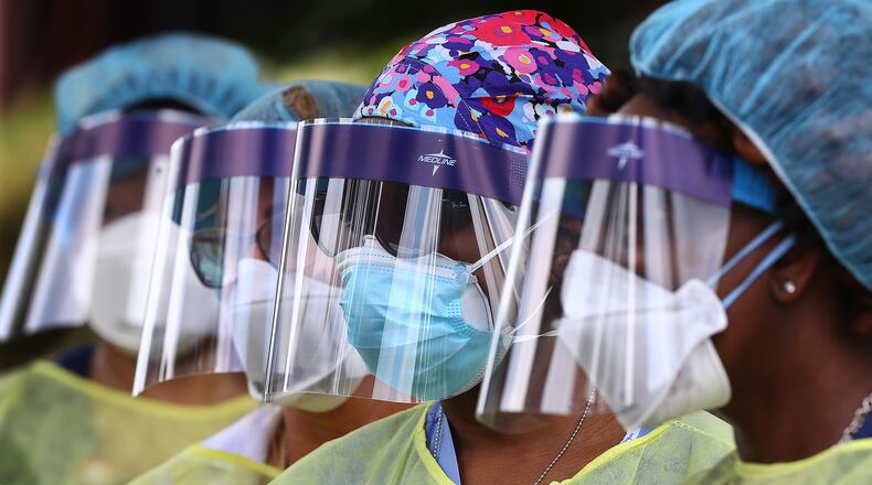Some of the more than two dozen specimen collection volunteers line up to begin taking hundreds of free COVID-19 tests at a pop-up site at the House of Hope on Monday, May 4, in Decatur. Pastors, local physicians, health ministers, and other community leaders united to encourage area residents to get tested with more than 200 motorists arriving for the opening. (CURTIS COMPTON / ccompton@ajc.com)