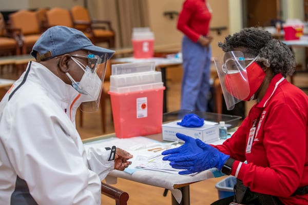 In this file photo, DeKalb County Board of Health medical worker Sandra Armstead, right, explains a few possible symptoms of the COVID-19 vaccination to Army Veteran and Rockdale County resident Larry Mitchell. She administered the vaccine to him during a DeKalb County Board of Health and Delta Sigma Theta Sorority event at the Lou Walker Senior Center in Stonecrest. (Alyssa Pointer / Alyssa.Pointer@ajc.com)