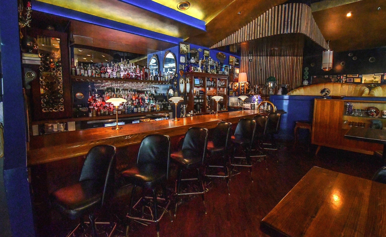 Douglas Hines, co-owner and interior designer of the Consulate, said people will sometimes try to purchase furniture or decorative elements from the restaurant, requests that he always declines. A 1950s glass cabinet near the bar is one of the most requested items, Hines said. (Chris Hunt for The Atlanta Journal-Constitution)