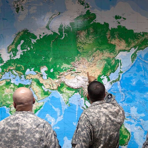 FILE - Soldiers look at a world map as they wait to board a flight in Manas, Kyrgyzstan, on the way home after completing a deployment in Afghanistan, Thursday, Aug. 11, 2011. (AP Photo/David Goldman, file)