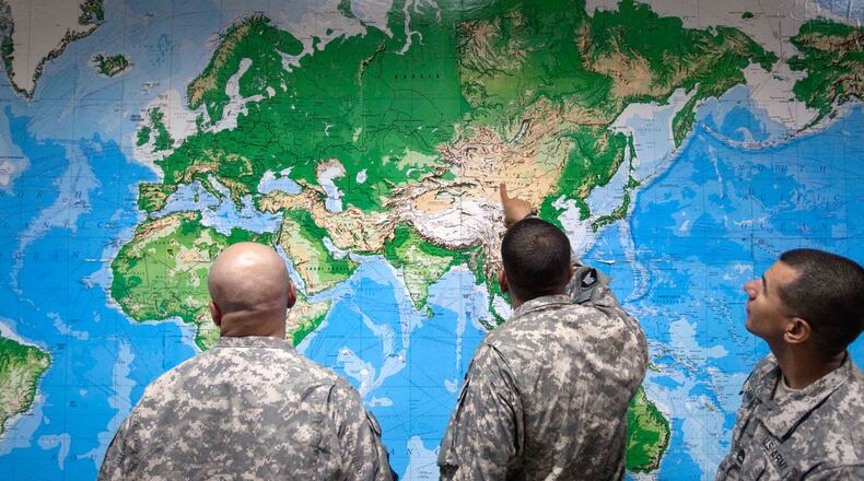 FILE - Soldiers look at a world map as they wait to board a flight in Manas, Kyrgyzstan, on the way home after completing a deployment in Afghanistan, Thursday, Aug. 11, 2011. (AP Photo/David Goldman, file)