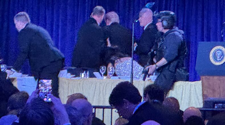 U.S. Secret Service agents surround President Donald Trump, third from left, as he is taken from the stage after a shooting incident outside the ballroom during the White House Correspondents Dinner, Saturday, April 25, 2026, in Washington. (AP Photo/Mark Schiefelbein)