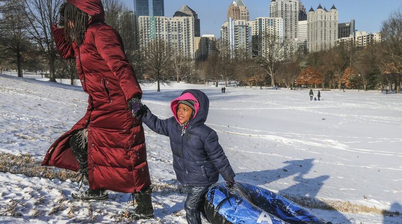 Jamila Cola and daughter, Zayna-4 head to the top of the hill with a tube at Piedmont Park on Wednesday morning, Jan. 17, 2018. Metro Atlanta schoolchildren got to enjoy a snow day, but for many, that now includes some learning time — online — in addition to the playtime outside. JOHN SPINK/JSPINK@AJC.COM