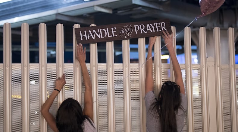 Las Vegas residents (from left) Elisbeth Apcar and Dashenka Giraldo put up a sign reading “Handle With Prayer” at a makeshift memorial at the northern end of the Las Vegas Strip on Oct. 4, 2017, in Las Vegas. On Oct. 1, Stephen Paddock killed 58 people and injured nearly 500 after he opened fire on a large crowd at the Route 91 Harvest country music festival. The massacre is one of the deadliest mass shooting events in U.S. history. DREW ANGERER / GETTY IMAGES