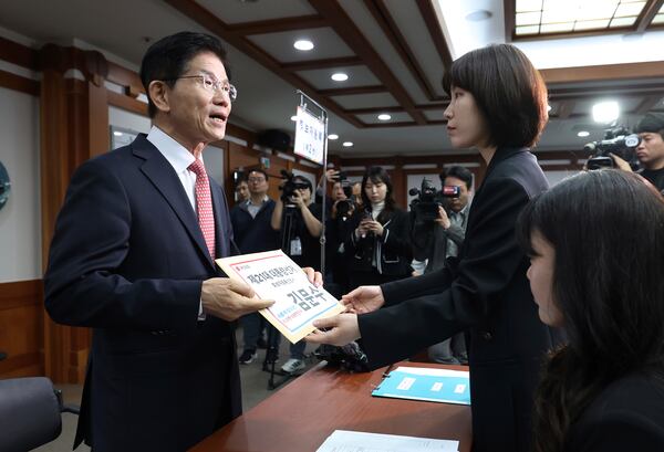 South Korea's People Power Party's presidential election candidate Kim Moon Soo, left, submits documents to register as a candidate to run in the June 3 presidential election, at the National Election Commission, Gwacheon, South Korea, Sunday, May 11, 2025. The letter read "The 21st Presidential election candidate registration application, Kim Moon Soo." (Yonhap via AP)