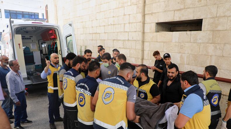 Members of the White Helmets carry the body of Mohammad Ghamira, a former White Helmets volunteer who died shortly after his release from jail, before his burial in the village of al-Haffa, Latakia province, Syria, Monday, Aug. 17, 2026. (AP Photo)