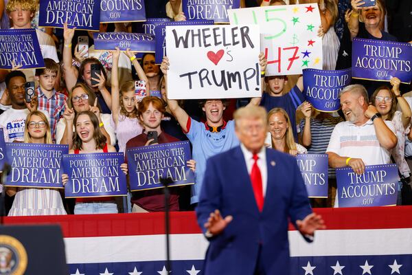 A supporter holds a “Wheeler Loves Trump” sign as President Donald Trump speaks at Wheeler High School on Wednesday. (Arvin Temkar/AJC)