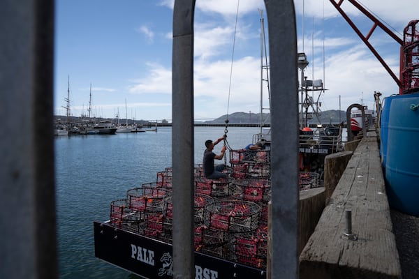 Hunter Nguyen, center right, and Jonathan Tin, load crab traps onto the boat Pale Horse at Pier 45 in San Francisco, Thursday, April 10, 2025. The boat's crew is trying out pop-up gear aimed at preventing whale entanglements. (AP Photo/Emily Steinberger)