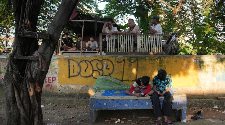 Teenage boys use their mobile phone in Jakarta, Indonesia, March 16, 2026. (AP Photo/Dita Alangkara)