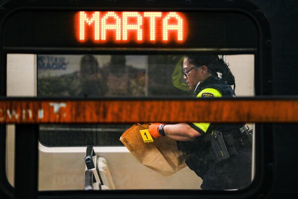 A MARTA police officer collects evidence from a train at the Midtown station Friday. (Ben Hendren for the AJC)