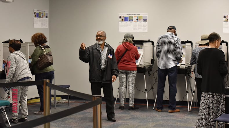 Volunteer Alfred Leblanc (center) directs early voters at the Gwinnett County Voter Registrations and Elections Office in Lawrenceville on Thursday, October 18, 2018. HYOSUB SHIN / HSHIN@AJC.COM