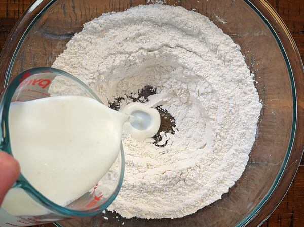 Senior AJC Food editor Monti Carlo pours buttermilk into a bowl with flour, salt and baking soda.