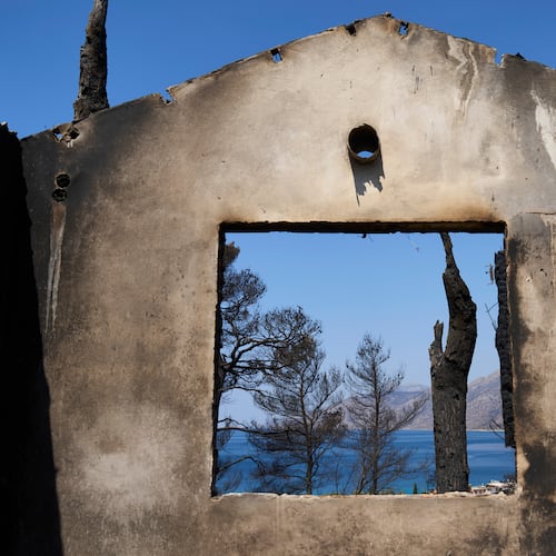 The sea is visible through the remains of a house destroyed by a wildfire in Porto Germeno, northwest of Athens, Greece, Tuesday, Aug. 4, 2026. (AP Photo/Petros Giannakouris)
