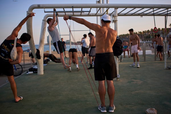 People work out in an open-air gym next to the beach in Barcelona, Spain, Tuesday, June 25, 2025. (AP Photo/Emilio Morenatti)
