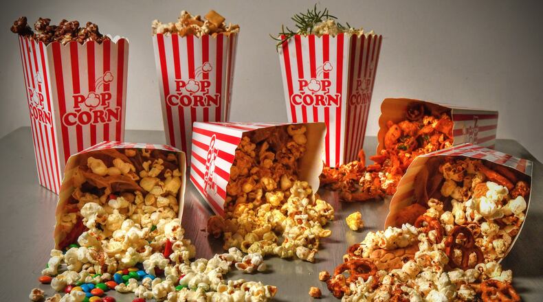 You have a choice of movies, so don't settle for plain old popcorn. Creative options include (back row from left) Dark Chocolate Sea Salt Popcorn, Sushi Popcorn, Olive Oil Popcorn with Garlic, Rosemary, and Parmesan; and (on their sides from left) Deluxe Movie Night Popcorn, Curry-Lime Popcorn, Frito Pie Popcorn and Hurricane Popcorn. (Styling by Susan Puckett / Chris Hunt for the AJC)