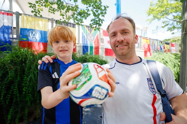 Ian Kerr and his son Sonny Kerr pose for a photo in Decatur Square, where they came to town for the World Cup round of 32 match between England and RD Congo on Monday, June 29, 2026. Ian Kerr believes that England will at least reach the quarterfinals in the knockout rounds. (Miguel Martinez/AJC)