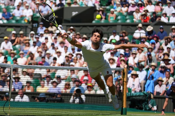Carlos Alcaraz of Spain returns the ball to Taylor Fritz of the U.S. during the men's semifinal singles match at the Wimbledon Tennis Championships in London, Friday, July 11, 2025.(AP Photo/Joanna Chan)