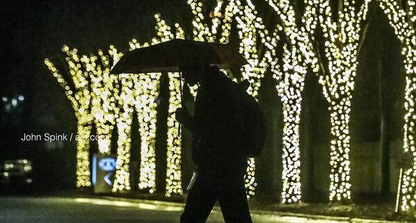 Aaron Long strolls past the Christmas lights at 1180 Peachtree in the rain.