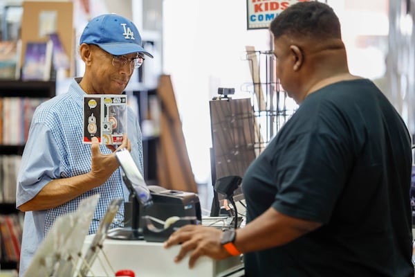 Anthony Gunter interacts with Tony Cade, owner of Challenges Games and Comics, as he pays for comic books and a Star Wars POP BB-8 on Wednesday, August 19, 2026. Gunter, a 14-year client, expresses his happiness at seeing the store reopen after its move from Northlake Mall. (Miguel Martinez/AJC)