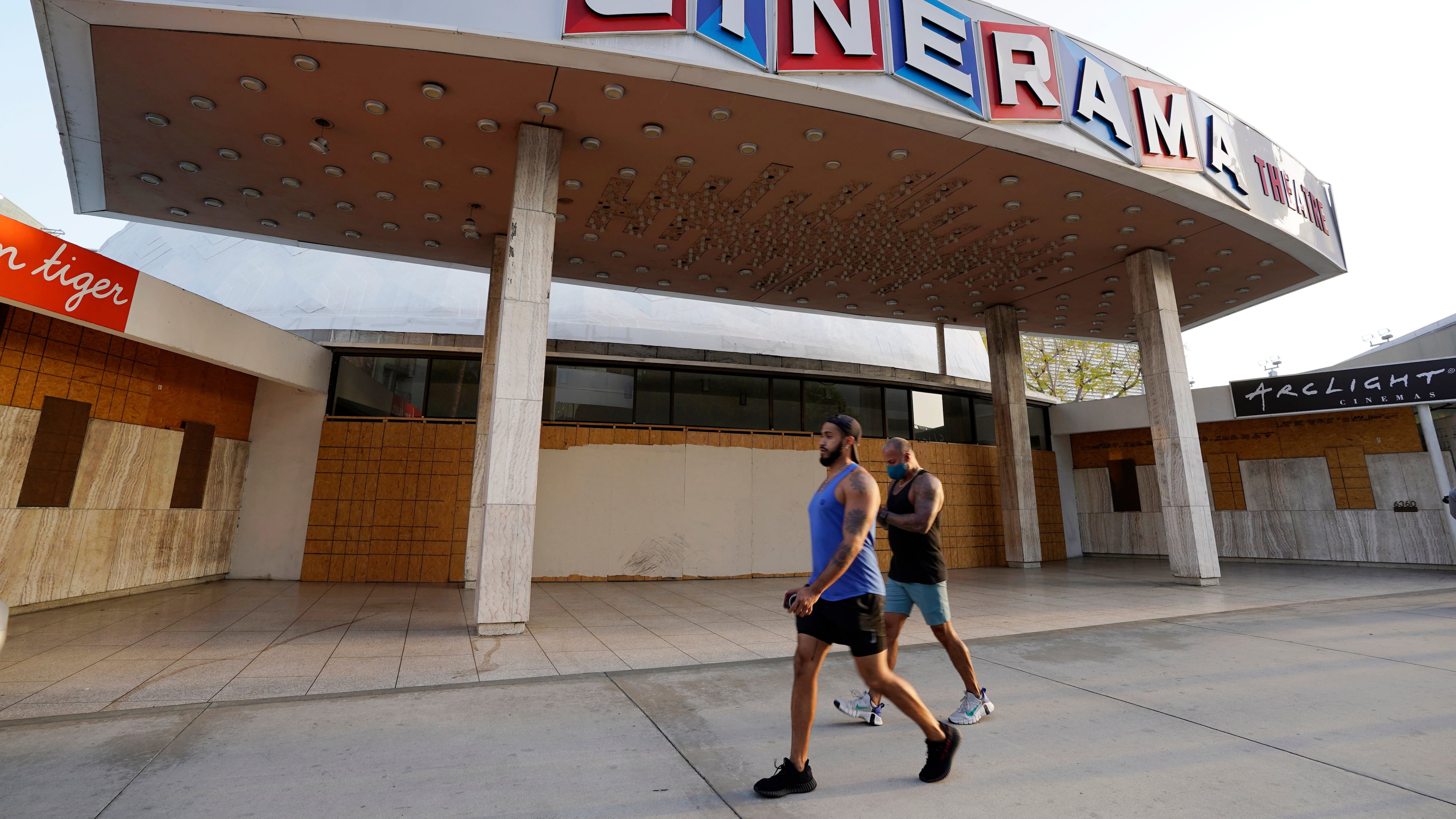 FILE - Pedestrians walk past the boarded up and closed Cinerama Dome movie theater, April 12, 2021, in Los Angeles. (AP Photo/Chris Pizzello, File)