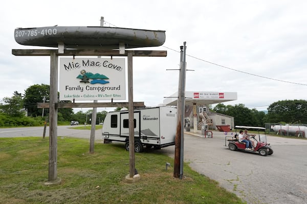 Campers ride a golf cart to the Mic Mac Cove Campground, Wednesday, July 9, 2025, in Union, Maine, where police have used the campground to access Crawford Pond to investigate the murder of a woman last seen paddleboarding on the pond. (AP Photo/Robert F. Bukaty)