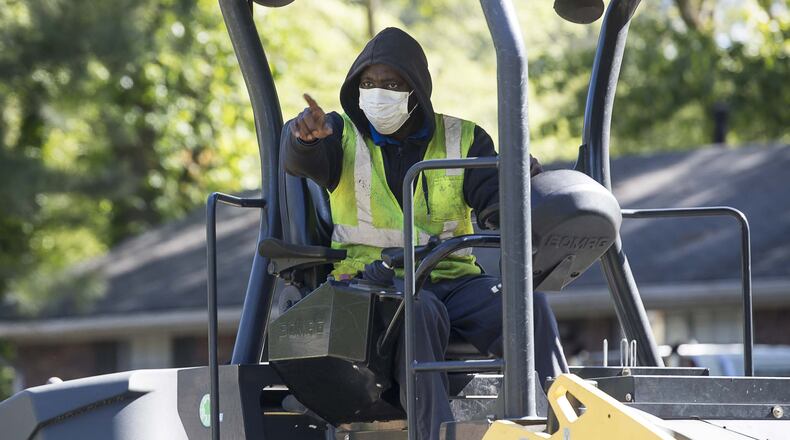Wearing a medical mask, H.E.H. Paving roller operator Charles Barker works with crews as they lay asphalt on Gwendon Terrace in Decatur. The paving project is part of the DeKalb County Special Purpose Local Option Sales Tax. (ALYSSA POINTER / ALYSSA.POINTER@AJC.COM)