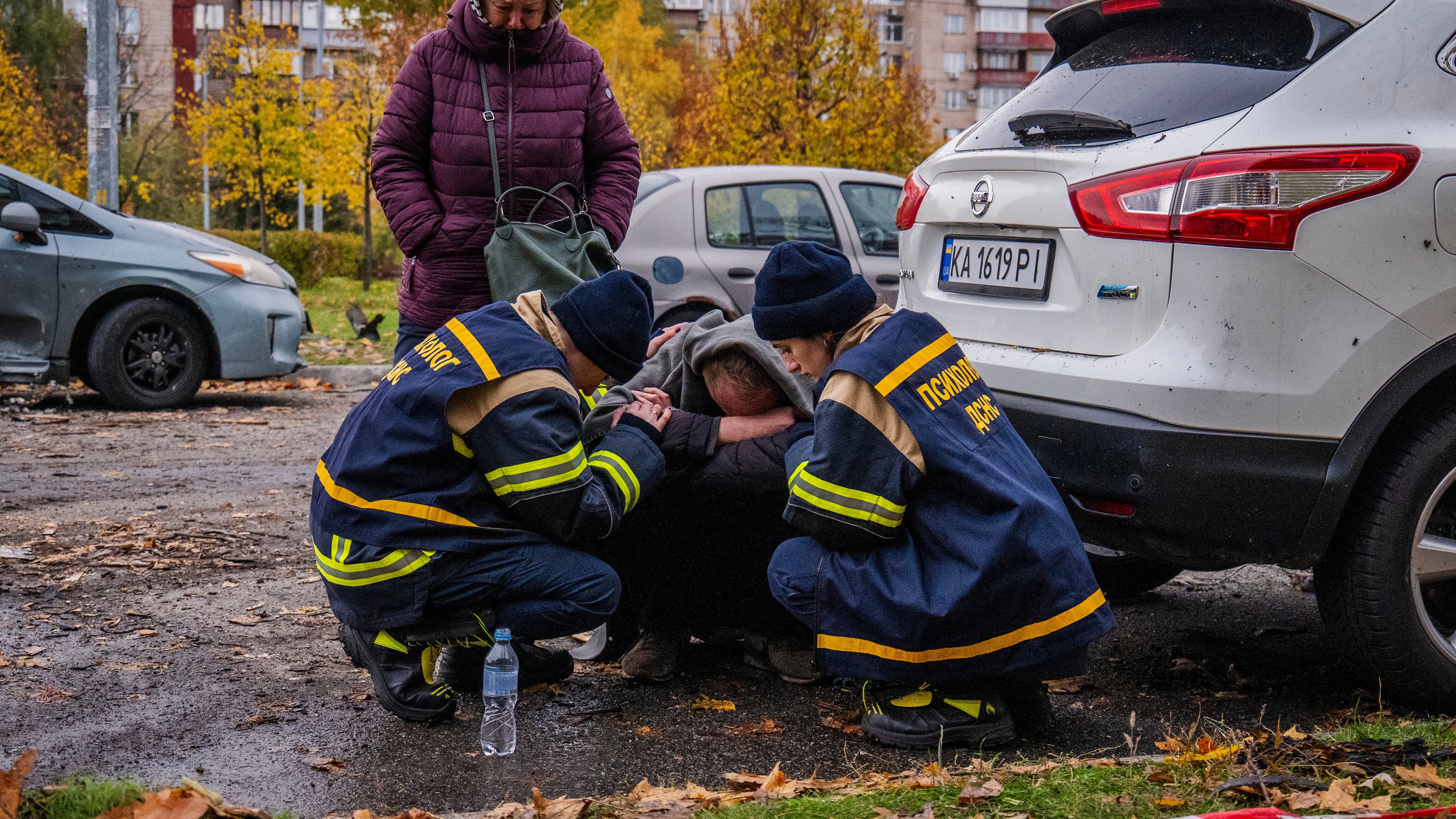 Emergency workers comfort a man who lost his son in Russia's drone attack that hit residential buildings in Kyiv, Ukraine, Sunday, Oct. 26, 2025. (AP Photo/Dan Bashakov)